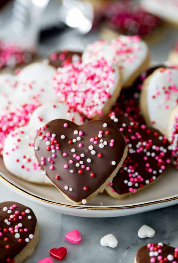 Valentine Cookies are made with a simple sugar cookie bases and are dipped in white and dark chocolate and sprinkled with nonpareils (for a great, crunchy texture!) or sprinkles.  These are the perfect Valentine’s Day dessert!