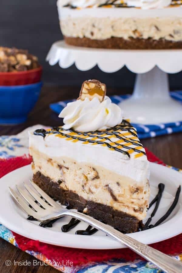 An easy no bake cheesecake loaded with candy bar chunks makes this Snickers Cheesecake Brownie Cake an impressive dessert to end dinner with