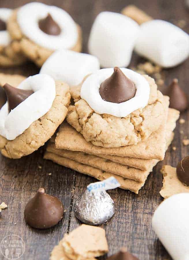 Peanut butter s’mores cookies have a peanut butter graham cracker filled cookie, topped with a gooey marshmallow, and a chocolate Hershey kiss. They combine the great taste of s’mores and peanut butter into a delicious cookie!