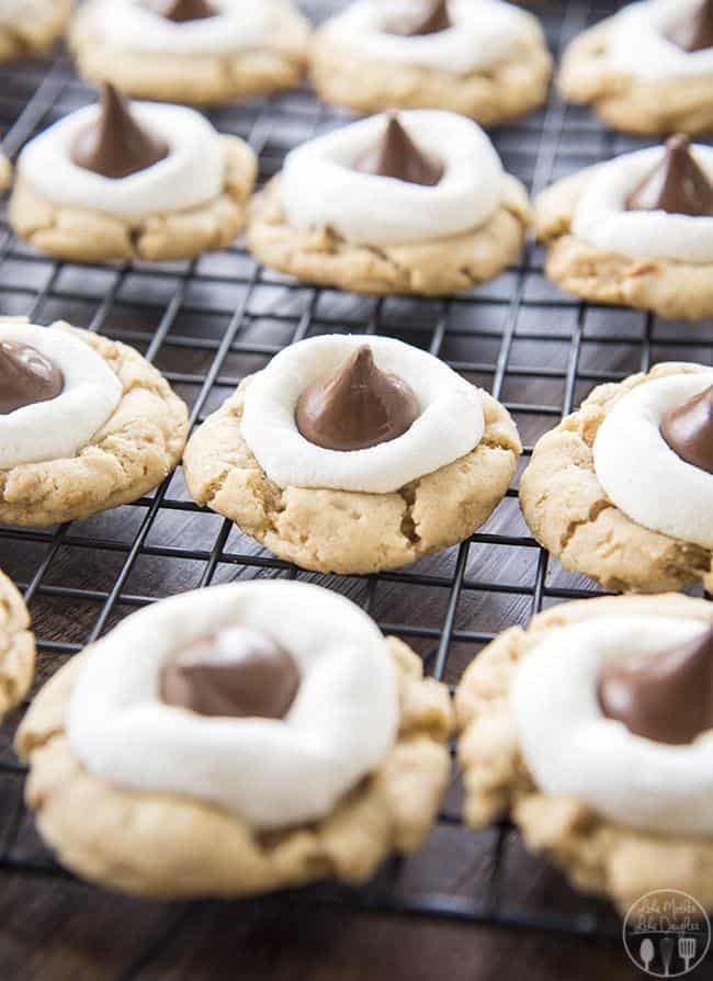 S'mores Cookies start with a graham cracker filled cookie base, topped with a gooey marshmallow, and a chocolate kiss - for your favorite s'mores flavors in a delicious and cute cookie!