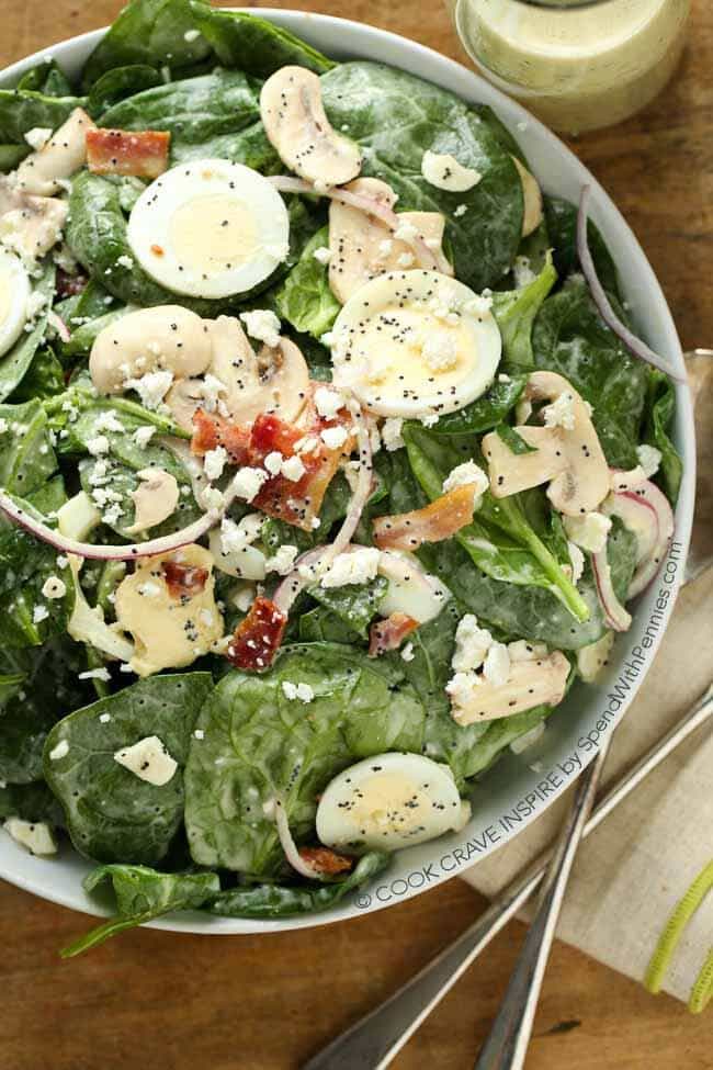 This Classic Spinach Salad recipe is topped with bacon, red onion, fresh mushrooms & boiled eggs. An easy homemade poppy seed dressing this is the perfect complement.  This makes a delicious side or is great with grilled chicken for a complete meal.