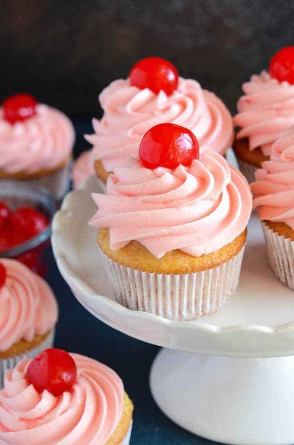 Perfect sweet vanilla and almond scented cupcakes are filled with bites of red maraschino cherries and topped with a gorgeous bright pink maraschino cherry frosting.