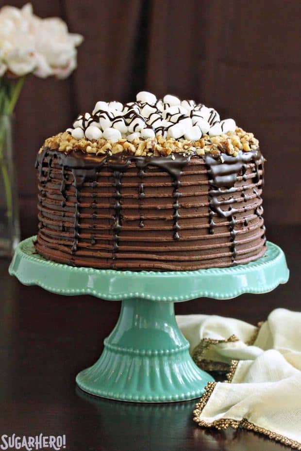 This Rocky Road Layer Cake is chocolate overload, in the best way possible! Moist chocolate cake is layered with a rich filling of marshmallows, nuts, and chocolate ganache. A glorious collection of marshmallows, nuts, ganache, and chocolate buttercream completes this indulgent dessert.