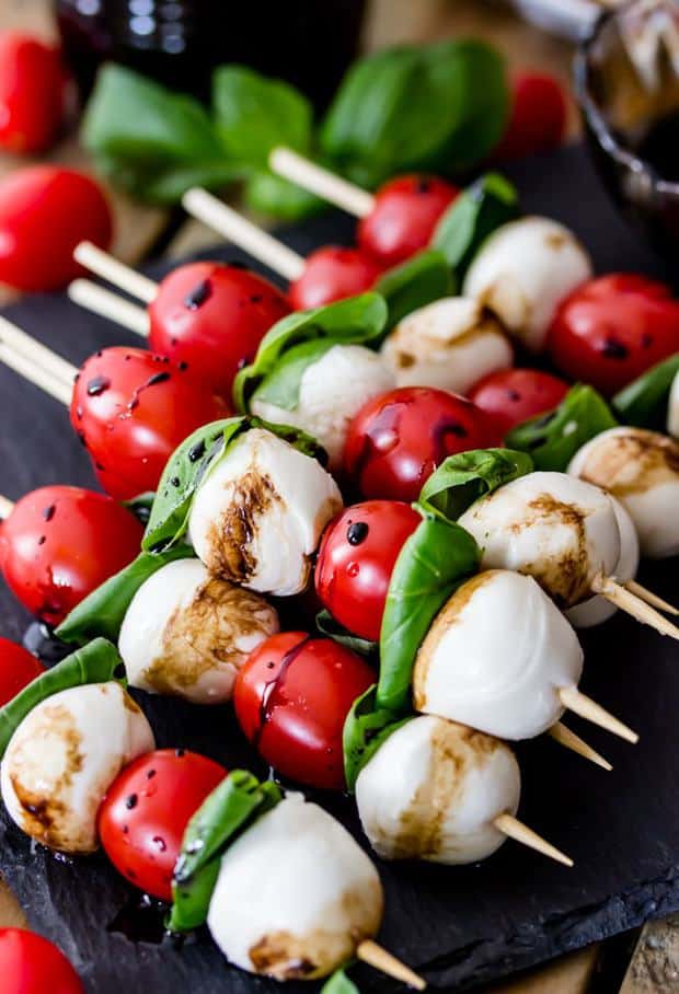 Caprese Skewers are 4 ingredient appetizers that are so simple to make but guaranteed to impress! Made with cherry tomatoes, mozzarella, fresh basil, and an easy balsamic reduction, they imitate the classic Caprese salad, only made portable on a skewer!
