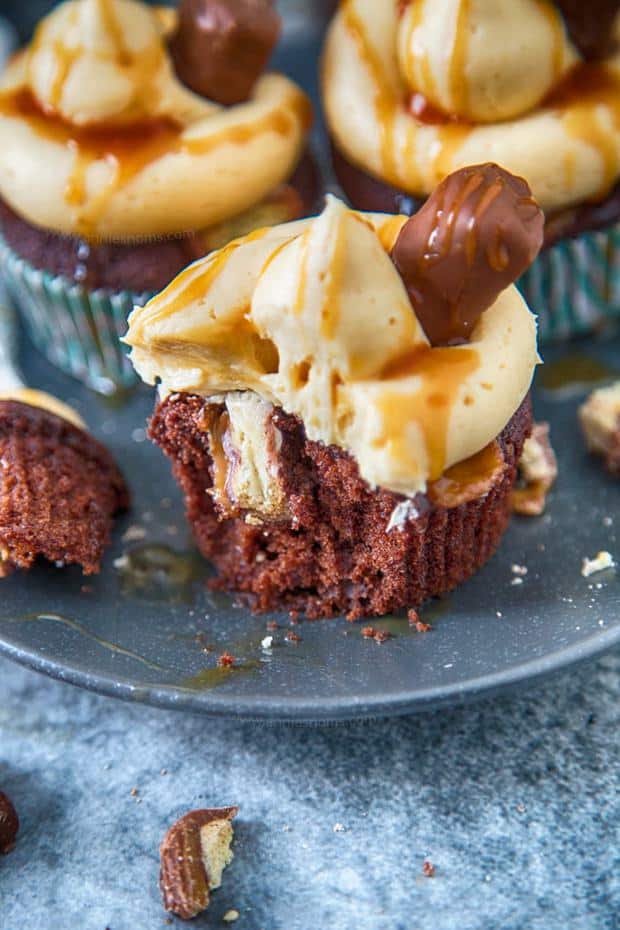 Twix Cupcakes are out of this world amazing! A soft, rich chocolate cupcake filled with bits of Twix and topped with caramel frosting and sauce!