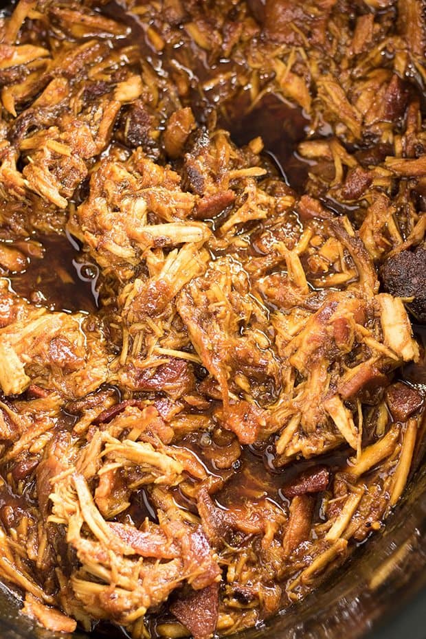 Crockpot Bourbon Bacon Pulled Pork – An easy recipe for the BEST ever crockpot pulled pork!  This pork is slow cooked to perfection with BBQ sauce, spices, bourbon, and the addition of bacon for even meatier barbecue flavor. We love this BBQ pulled pork recipe that makes slow cooker pulled pork tenderloin the most tender and flavorful!