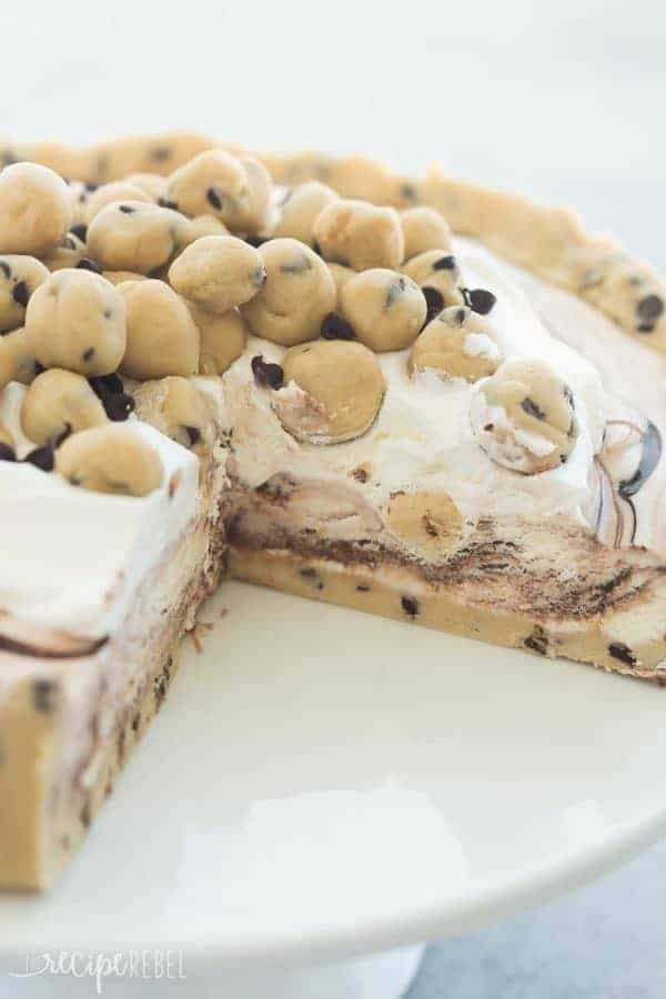 This Cookie Dough Ice Cream Cake is an easy, no bake dessert for a summer cookout or birthday party! Made on a cookie dough crust, filled with no churn ice cream and topped with chunks of cookie dough. Includes step by step recipe video