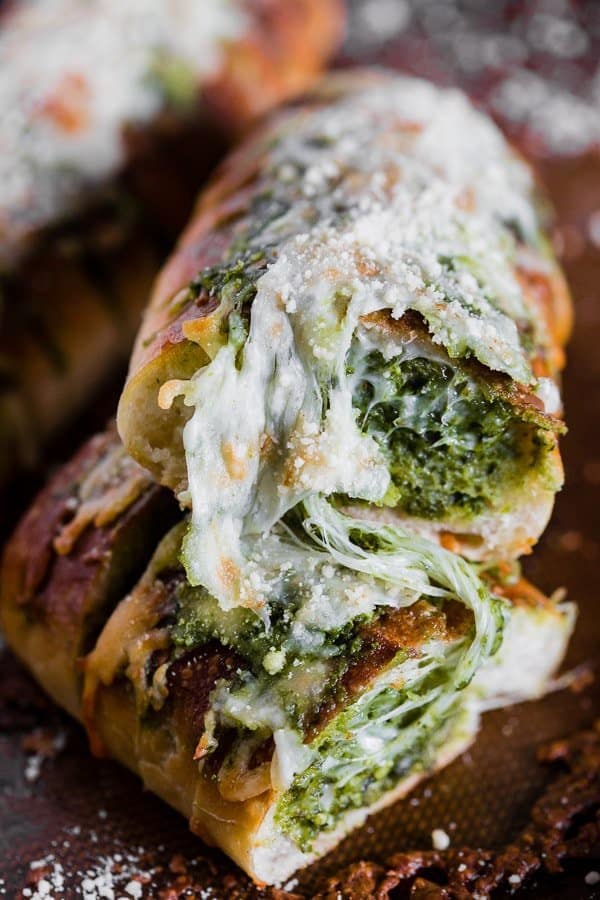 This cheesy pesto garlic bread is packed full of fresh garlic basil pesto and stringy mozzarella cheese. Super simple to make and full of flavor! You’ll love how easy this bread side dish is to make!