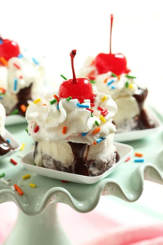 Creamy vanilla ice cream tops a fudge brownie base then is topped with warm hot fudge sauce, whipped cream and a cherry creating a fun mini dessert.  Easy to make, Hot Fudge Brownie Sundae Bites are perfect for a crowd and are little bits of heaven.