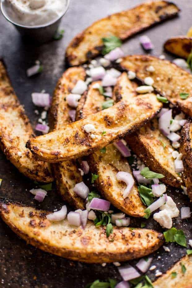 These Greek loaded baked potato wedges make a tasty appetizer or side dish. Served with tzatziki for dipping!