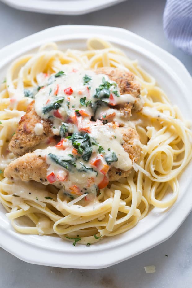 Tuscan Garlic Chicken is a family favorite! Tender and juicy crusted chicken served over noodles with a delicious creamy tuscan garlic sauce.