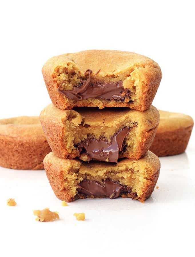 Cookie lovers unite! These ooey gooey golden brown cookie cups will blow your mind with their surprise melty Nutella filling! That’s right! Hidden INSIDE is a good teaspoon full of dreamy Nutella goodness. I don’t know about you but these chunky cookie cups give the old cookie a run for its money.