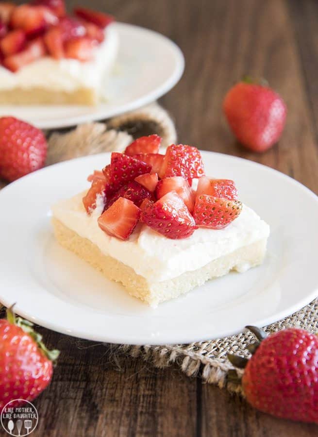 Thick and soft sugar cookie bars topped with whipped cream and strawberries for a delicious and easy treat like a strawberry shortcake in sugar cookie bar form!