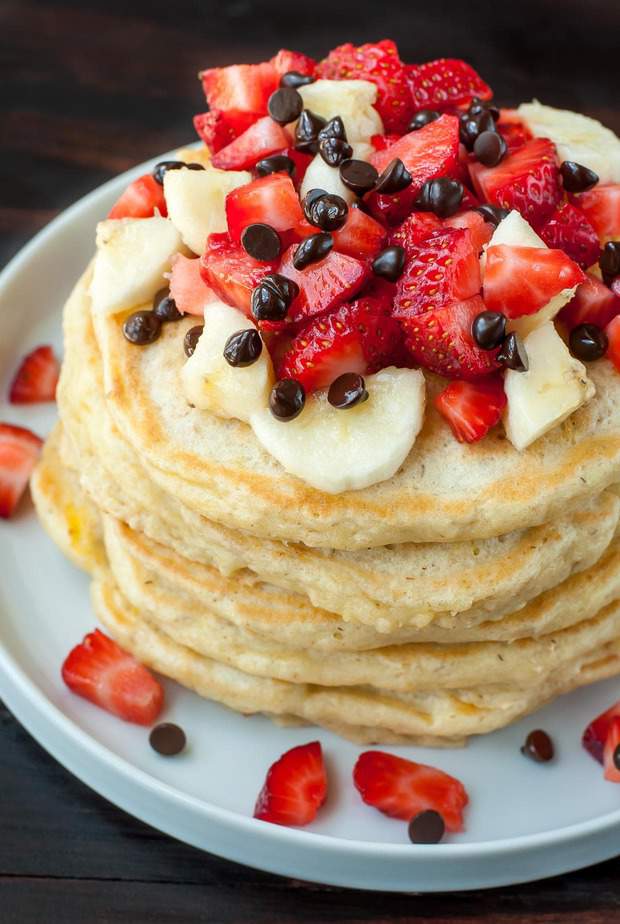 Perfectly fluffy oatmeal pancakes topped with banana, strawberries, and a kiss of dark chocolate chips, these Banana Split Pancakes are a healthy spin on dessert pancakes!