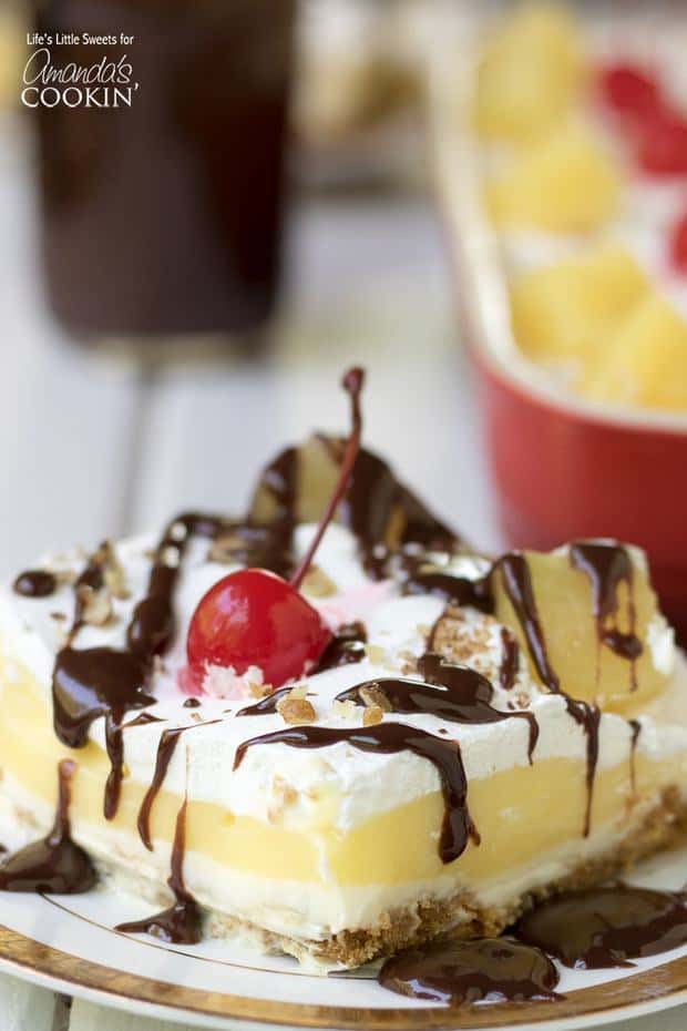 anana Split Dessert is a light and sweet Banana Cream Lush recipe topped with chocolate sauce, maraschino cherries, and pineapple. Enjoy this delightful dessert at any summer holiday, potluck or BBQ!