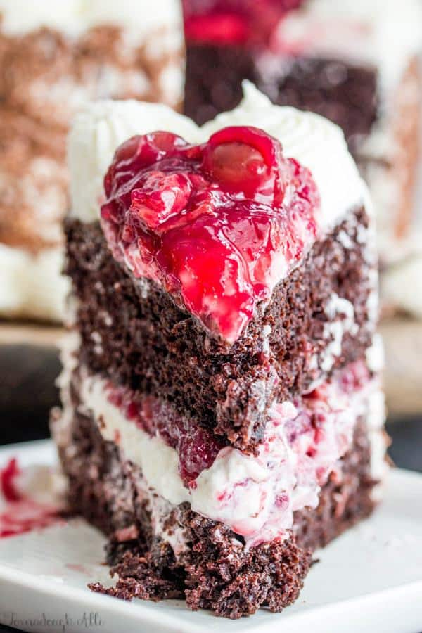 Moist chocolate cake is filled with a fluffy white frosting and cherries and covered and topped with more frosting, chocolate and even more cherries making this Black Forest Cake one addicting treat.