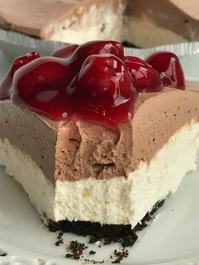 Black forest cheesecake pie is no bake and can be made in just minutes! Ready-to-use chocolate cookie crust with two layers of smooth cream pie filling. Top with a spoonful of canned cherry pie filling and you have a seriously amazingly delicious dessert loaded with chocolate, cherry, and cheesecake flavors.