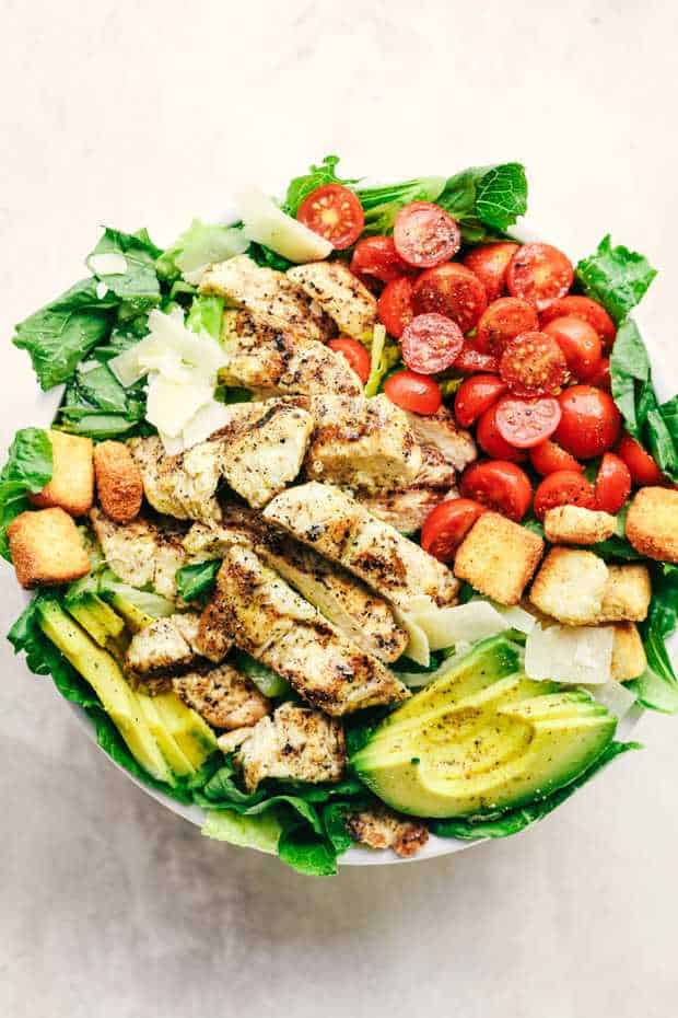 Grilled Chicken Caesar Avocado Salad is a mouthwatering classic salad with juicy grilled chicken,  crisp romaine lettuce, cherry tomatoes, avocado, and topped with shaved mozzarella and crunchy croutons!