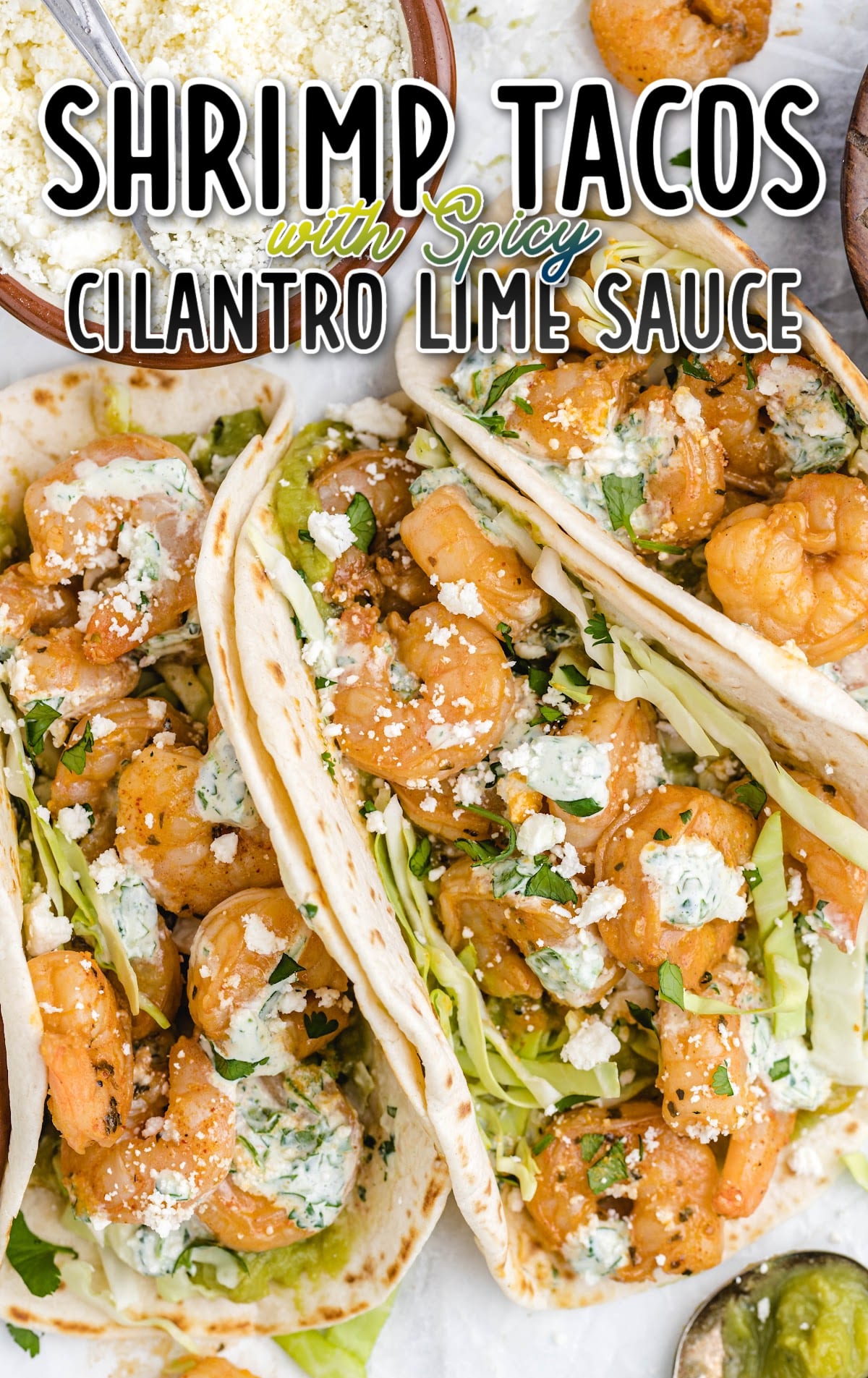 shrimp tacos on a plate with sauce, cilantro, and cheese