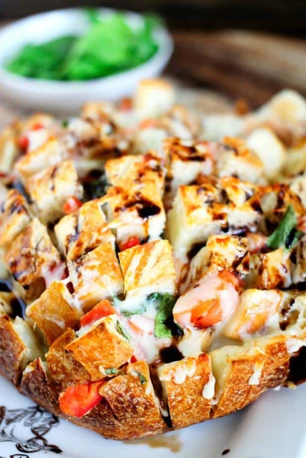 Caprese Stuffed Pull Apart Bread is fresh bread stuffed with delicious fresh tomatoes, basil, and mozzarella, then topped with a sweet and tangy balsamic glaze!