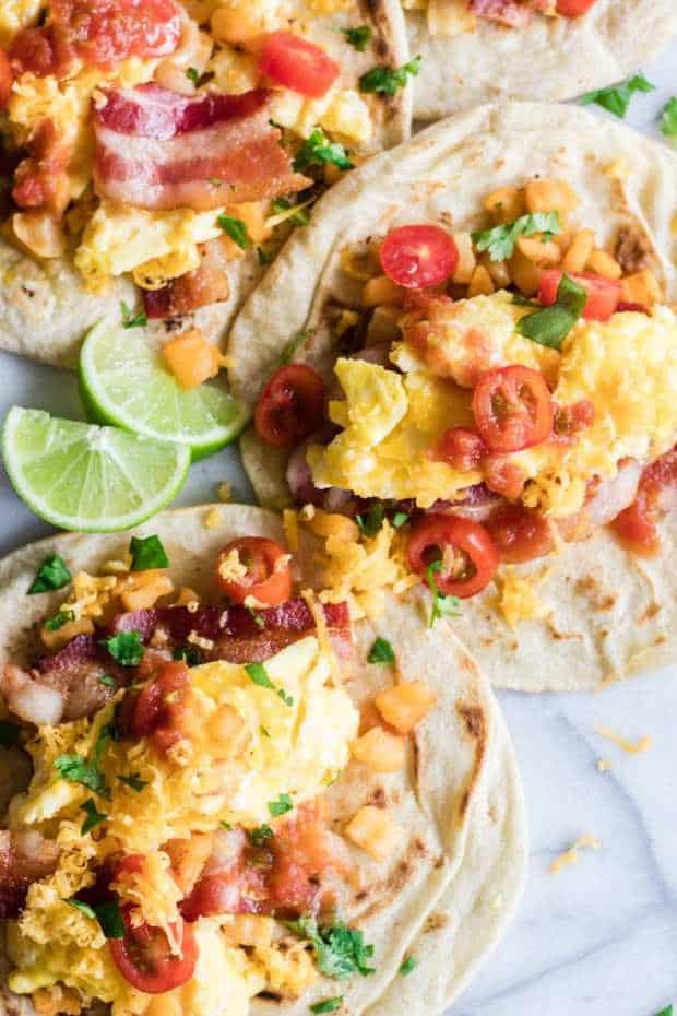Breakfast Tacos. A breakfast staple in Texas restaurants easily made at home! Tortillas layered with potatoes, crispy bacon, soft scrambled eggs and all the toppings! Filling and flavorful these tacos are the BEST way to start the day.