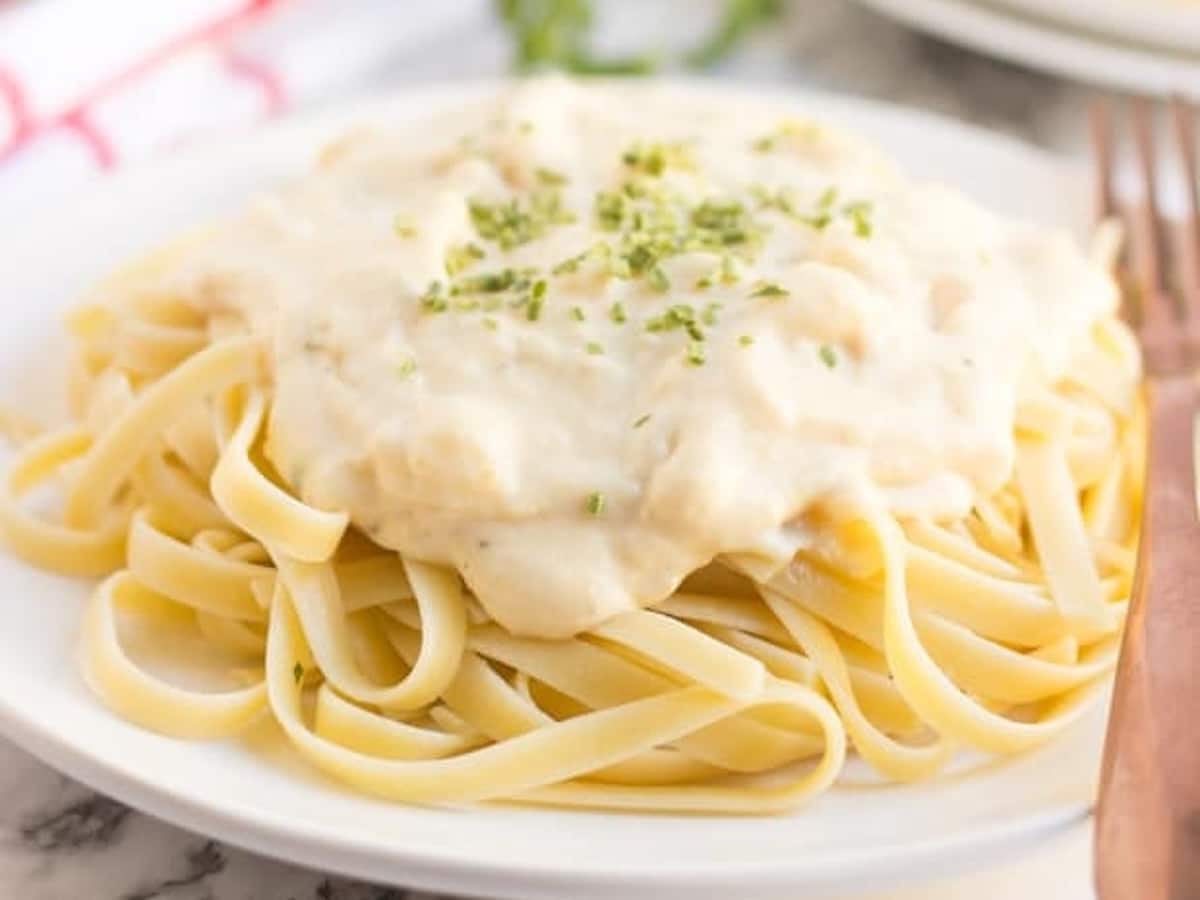 A plate of fettuccine topped with creamy Laughing Cow alfredo sauce and a sprinkle of freeze-dried chives.