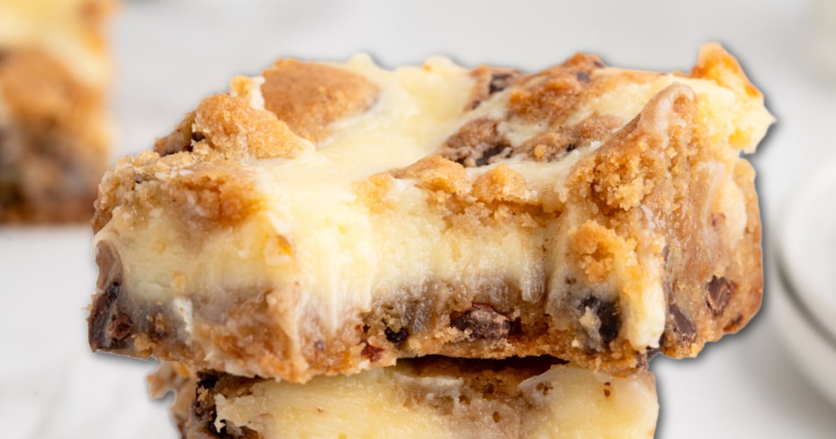 Close-up of a chocolate chip cheesecake bar showing the creamy cheesecake layer, golden cookie dough topping, and melty chocolate chips with a soft, gooey texture.