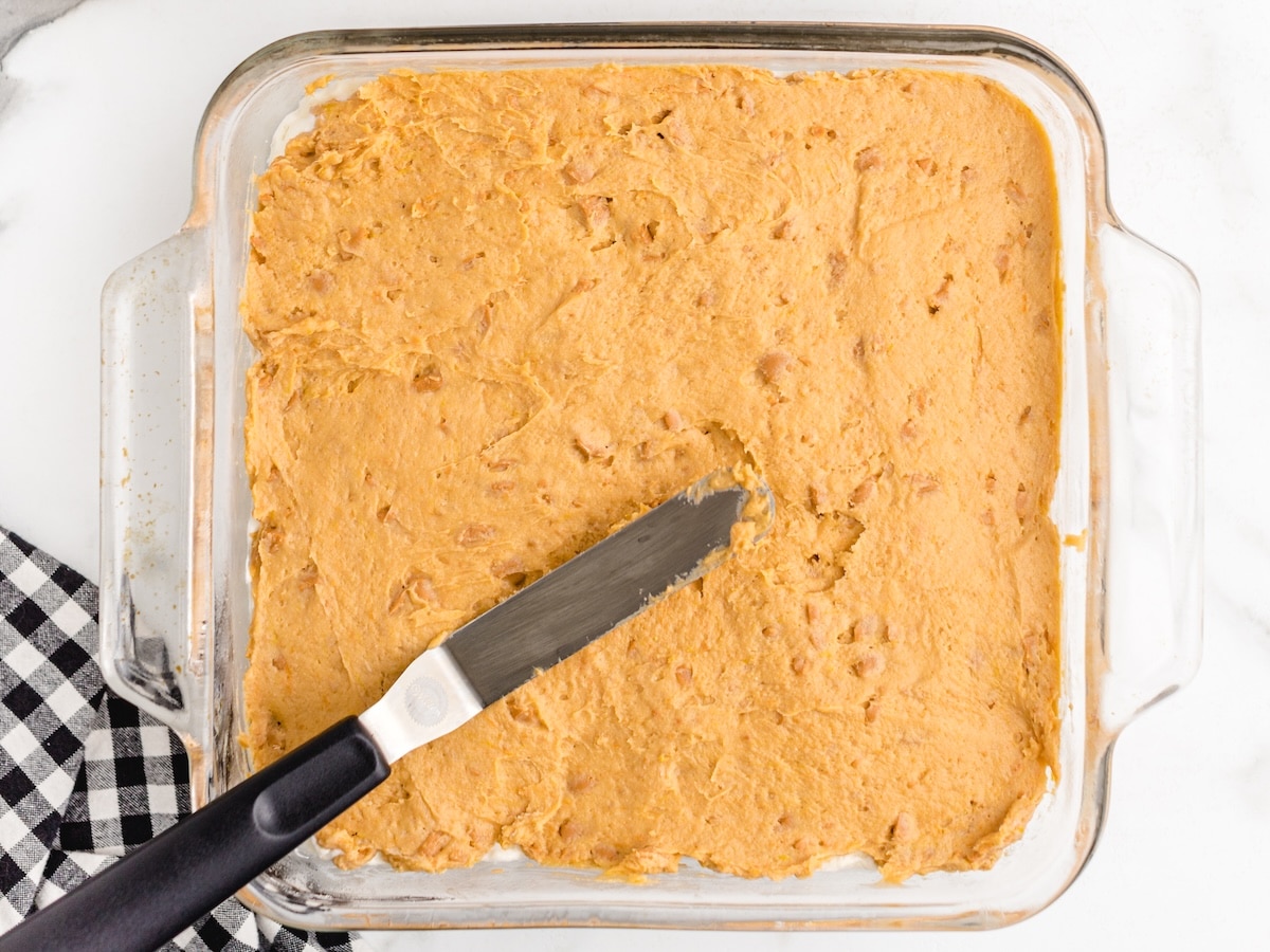 Butterscotch pudding layer with chopped butterscotch chips spread evenly over the cream cheese layer with an offset spatula.