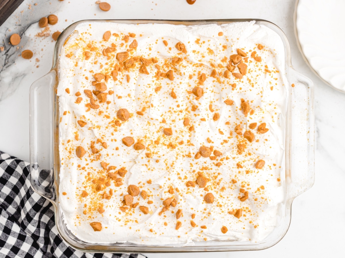 Finished Butterscotch Delight in a glass 8x8 dish, topped with whipped topping and sprinkled with chopped butterscotch chips.
