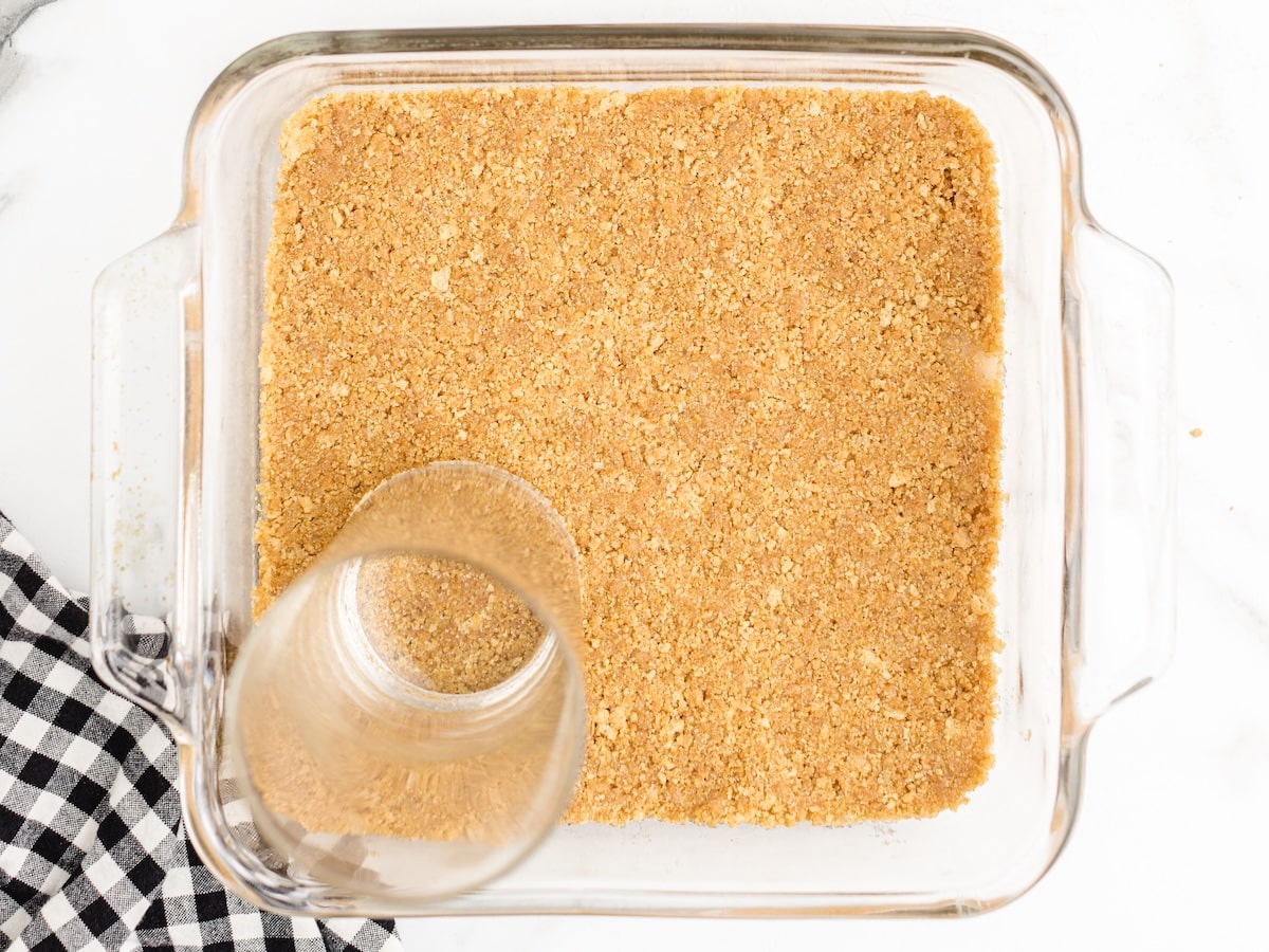 Graham cracker crust pressed into the bottom of a glass 8x8 baking dish, flattened with the base of a drinking glass.