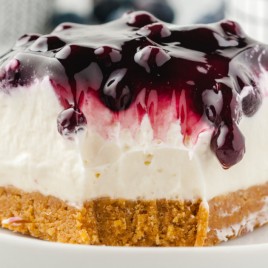 A cake with a dessert on a plate, with Blueberry and Cheesecake