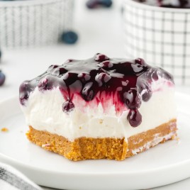 A slice of cake on a plate, with Blueberry and Cheesecake