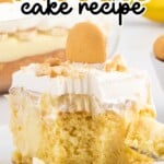A slice of banana pudding cake on a white plate, topped with whipped cream and a vanilla wafer, showing layers of moist cake, creamy banana pudding, and whipped topping.