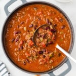 A large pot of homemade chili with a big ladle inside.