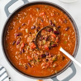 A large pot of homemade chili with a big ladle inside.