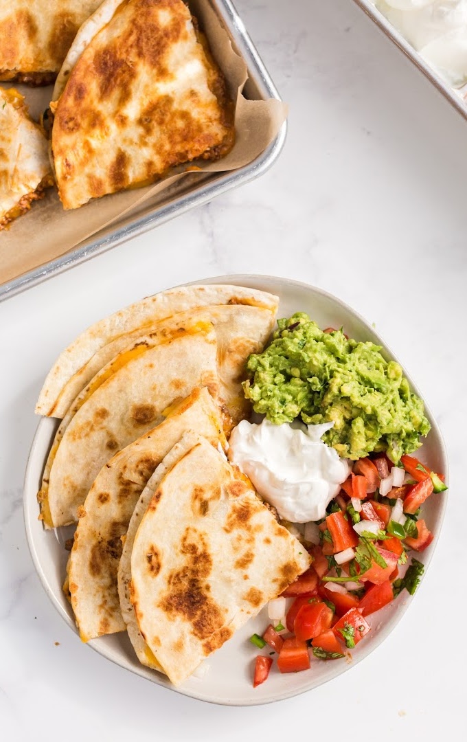 Cheesy Beef Quesadillas on plate with guacamole, salsa and sour cream