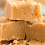 Old fashioned peanut butter fudge stacked into squares with a bowl of marshmallows and peanut butter.