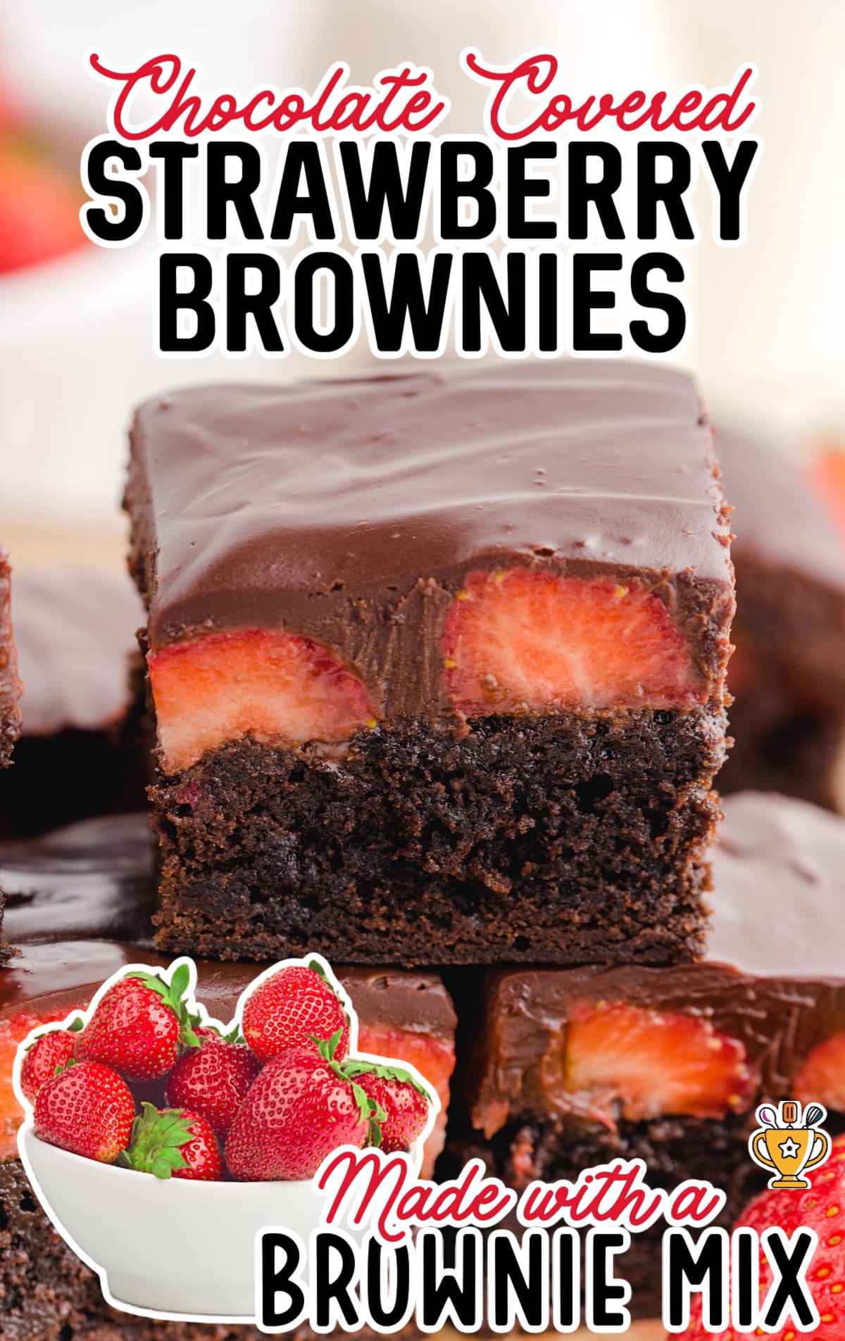Chocolate Covered strawberry brownies stacked and cut with a bowl of strawberries.
