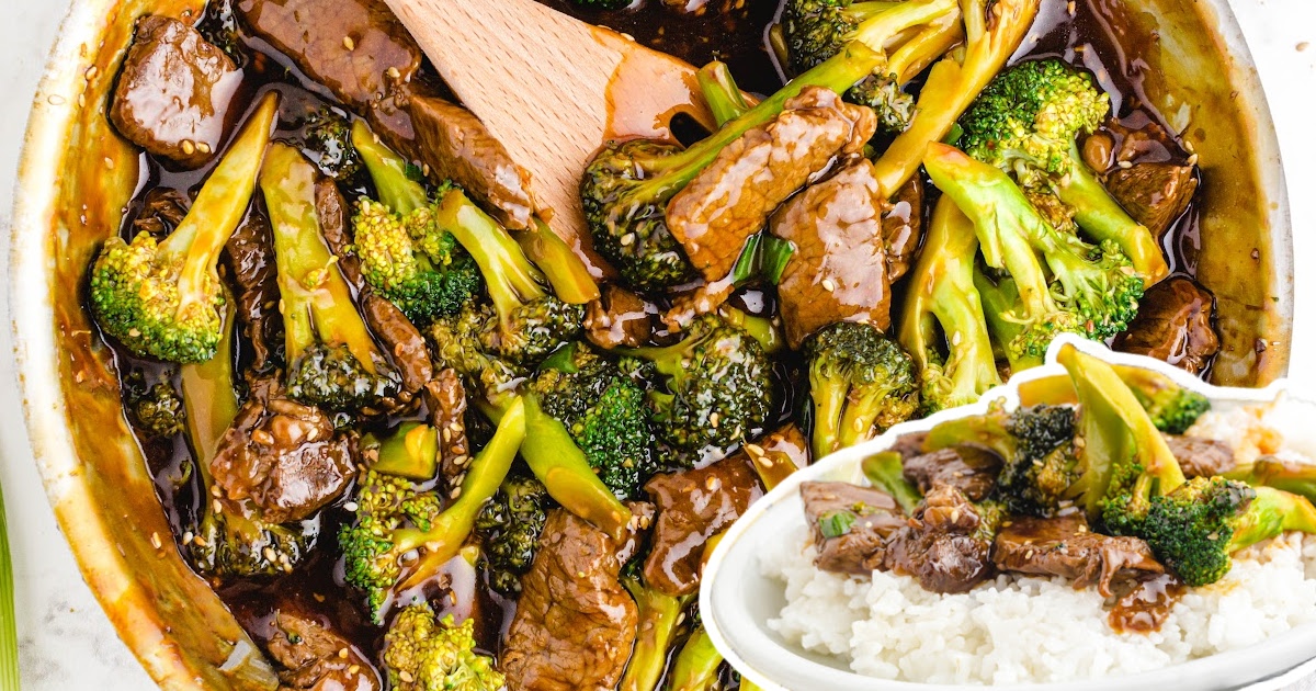 Close-up of beef and broccoli being stirred with a wooden spoon in a thick flavorful sauce with sesame seeds.