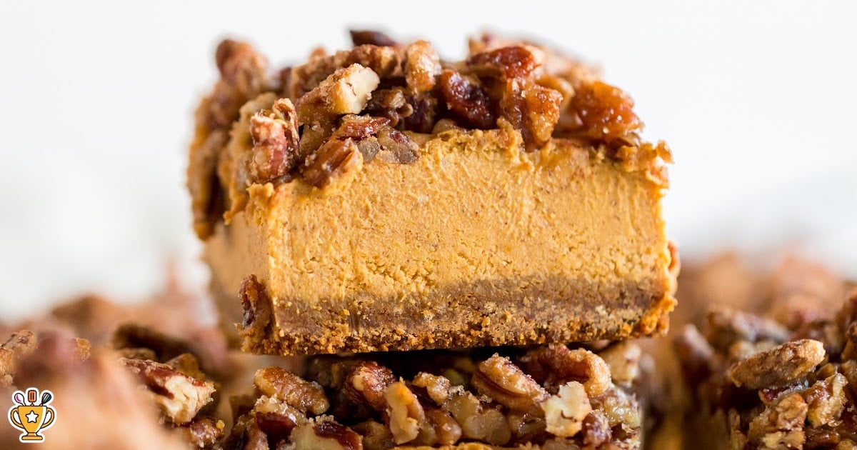 Freshly baked pecan-topped pumpkin cheesecake bars cooling on parchment paper before cutting into squares.
