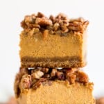 Pumpkin cheesecake bar topped with glazed pecans and layered over a spiced gingersnap crust. Text overlay lists ingredients including cream cheese, pumpkin puree, and gingersnap crumbs for this easy fall dessert recipe.