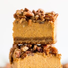 Pumpkin cheesecake bar topped with glazed pecans and layered over a spiced gingersnap crust. Text overlay lists ingredients including cream cheese, pumpkin puree, and gingersnap crumbs for this easy fall dessert recipe.
