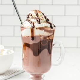 Recipe card for spiked hot chocolate showing ingredients like milk, dark chocolate chips, white chocolate chips, and walnut liqueur with rich whipped cream topping.
