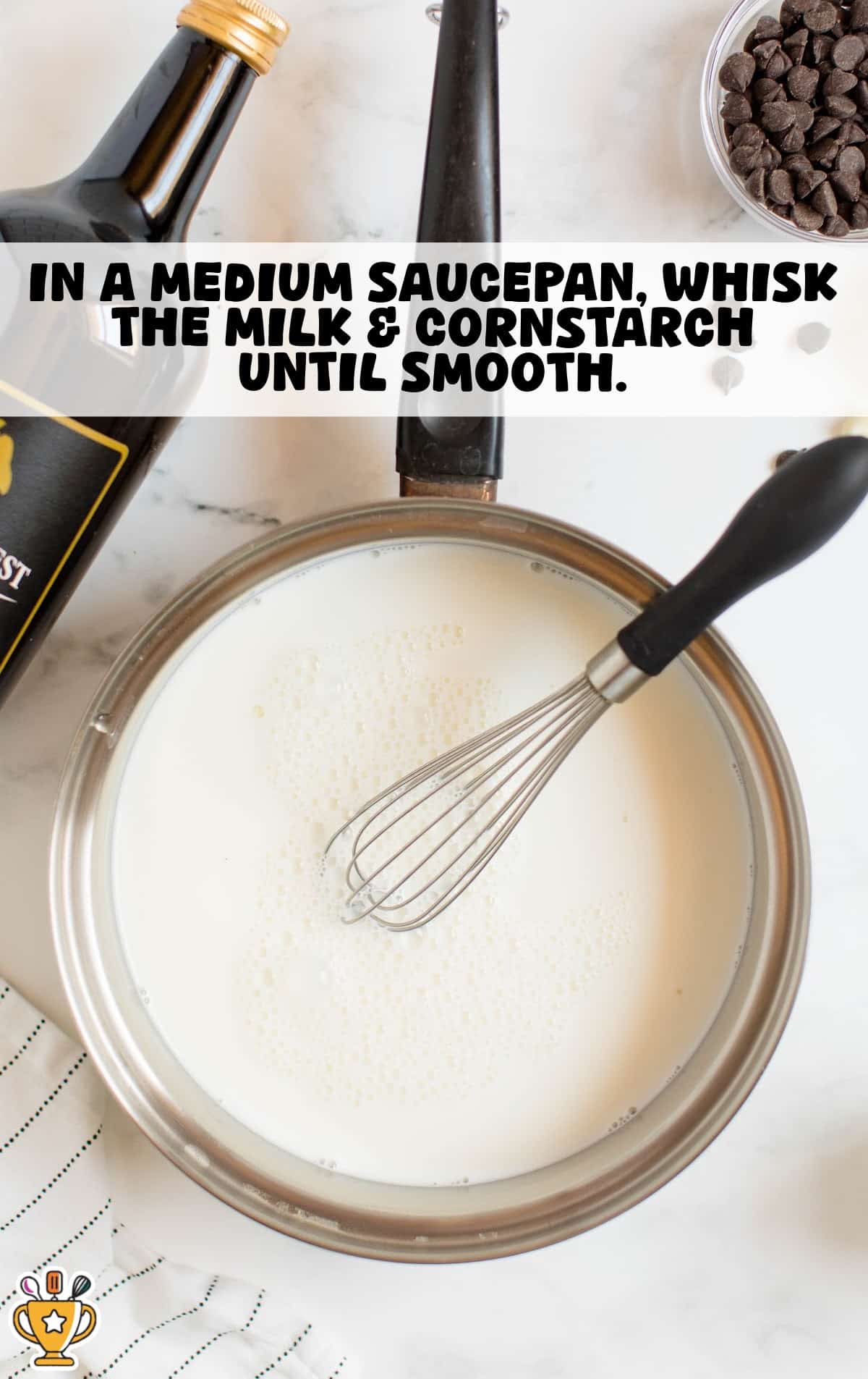 Step one of spiked hot chocolate recipe showing saucepan with milk and cornstarch being whisked smooth before adding chocolate and liqueur for a creamy hot cocoa base.