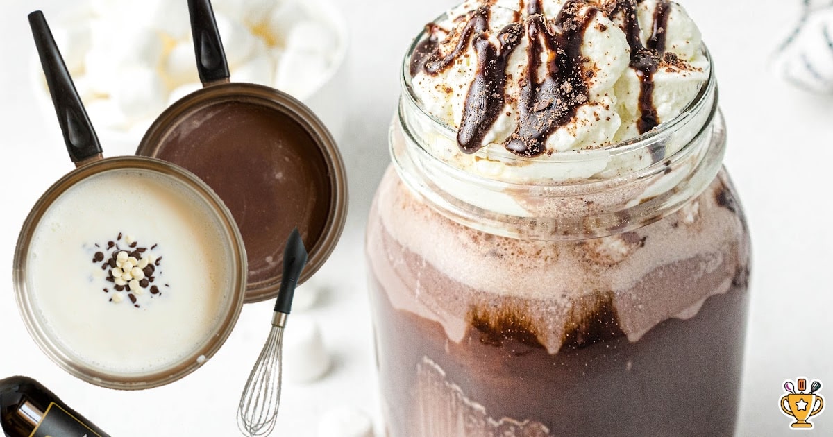Homemade spiked hot chocolate in a glass mug with layers of rich cocoa and cream, finished with whipped cream and shaved chocolate for the ultimate grown-up hot cocoa.