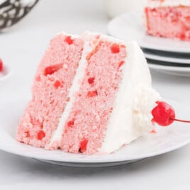 A slice of double layer cherry chip cake on a white dessert plate.