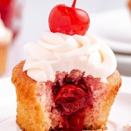 A close up of a piece of cake on a plate, with Cherry and Cupcake