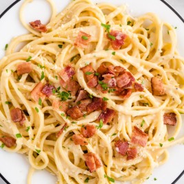 A plate of pasta with meat and vegetables, with Carbonara