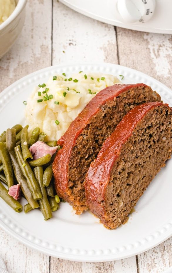 A piece of cake sitting on top of a plate of food, with Meatloaf and Bread