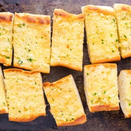 A tray of food with a slice cut out, with Bread and Garlic
